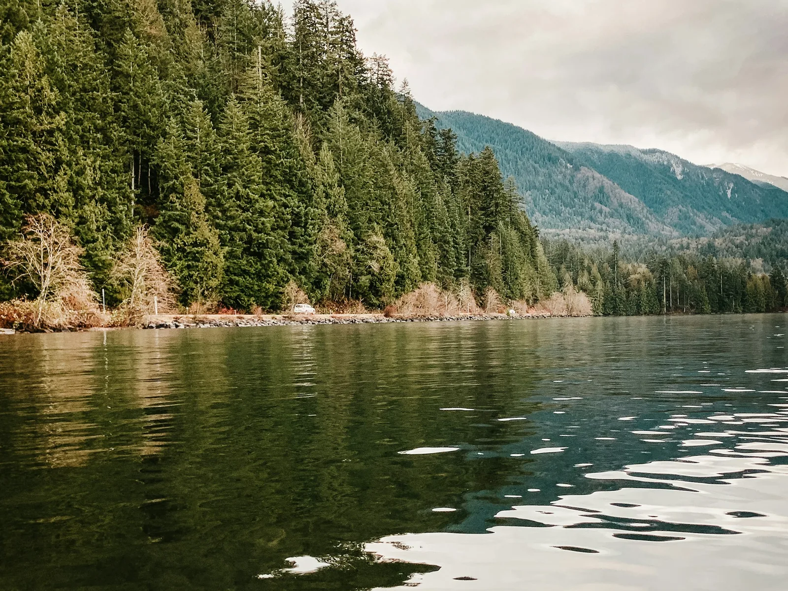 Cultus Lake in British Columbia, with forested shoreline and soft haze over the water.